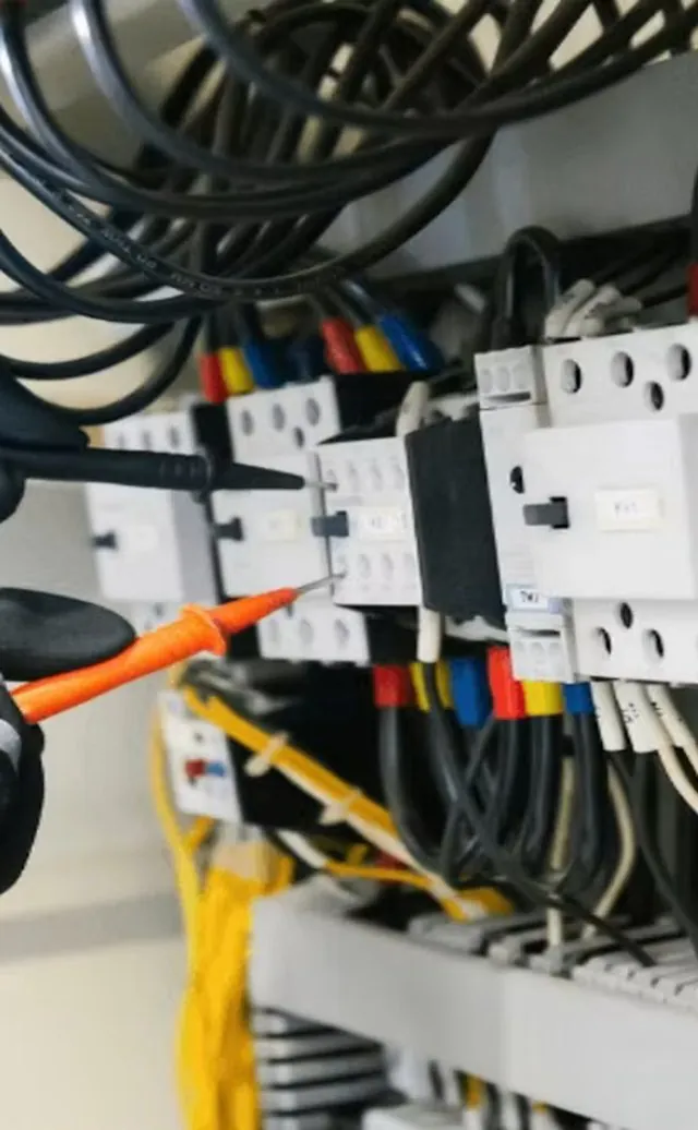 Electrician testing contactors inside a distribution board