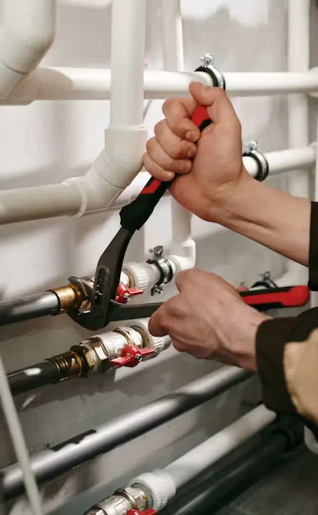 Plumber tightening a pipe fitting with a pipe wrench